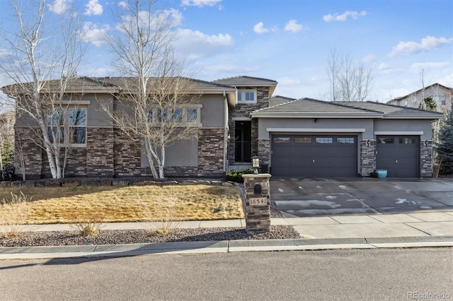 prairie-style house featuring concrete driveway, an attached garage, stone siding, and stucco siding