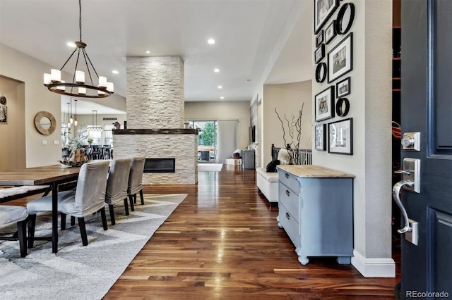 interior space with dark wood-type flooring, baseboards, recessed lighting, a fireplace, and a notable chandelier