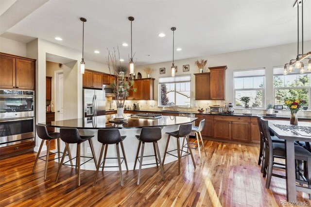 kitchen with a breakfast bar, dark countertops, brown cabinetry, and stainless steel appliances