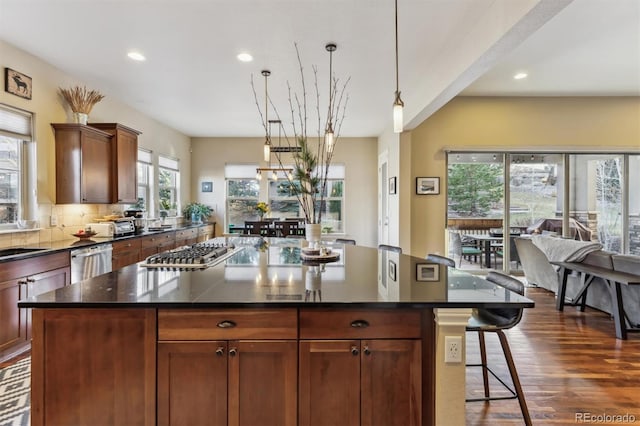 kitchen featuring stainless steel appliances, decorative backsplash, dark wood-type flooring, pendant lighting, and a kitchen bar