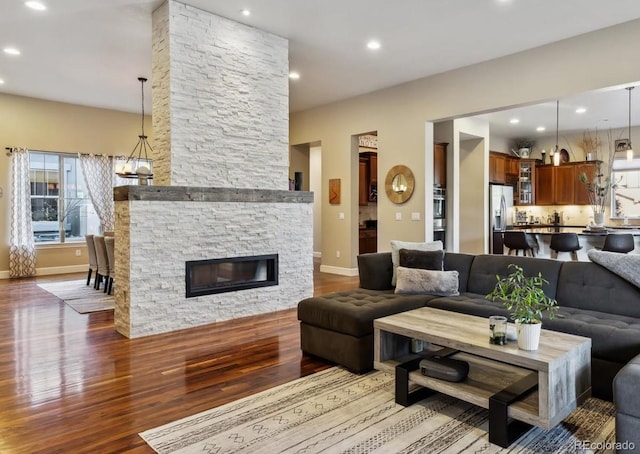 living room featuring recessed lighting, a stone fireplace, and wood finished floors