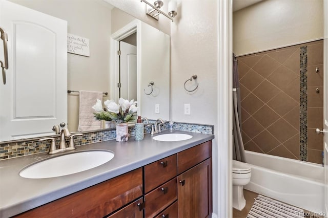 bathroom featuring a sink, shower / bath combo with shower curtain, toilet, and double vanity