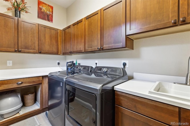 washroom featuring washing machine and clothes dryer, cabinet space, light tile patterned flooring, and a sink