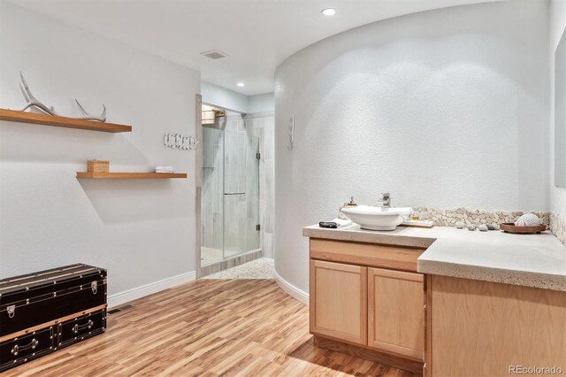 bathroom with visible vents, wood finished floors, a shower stall, baseboards, and vanity