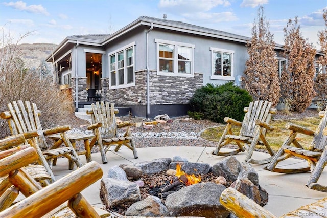 rear view of property with a patio, stone siding, and stucco siding