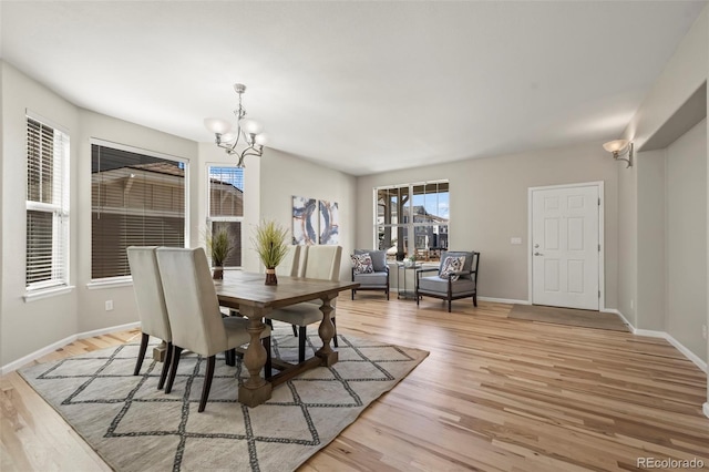 dining room with a chandelier, light wood finished floors, and baseboards