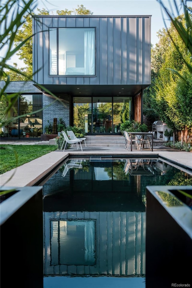 rear view of property featuring a patio and an outdoor pool