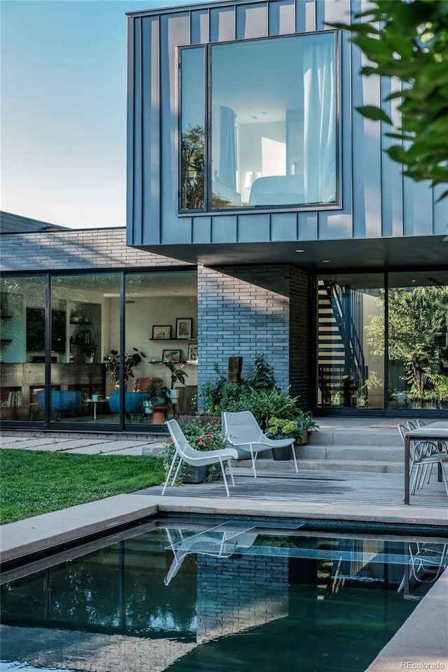 back of house with an outdoor pool and brick siding