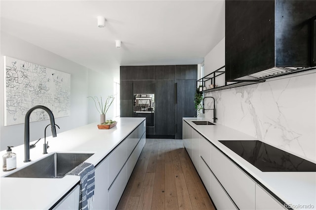 kitchen featuring white cabinets, light countertops, black electric cooktop, and a sink