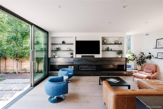 living room featuring a fireplace, recessed lighting, wood finished floors, and expansive windows