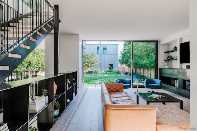 living room featuring stairway, floor to ceiling windows, built in shelves, and wood finished floors