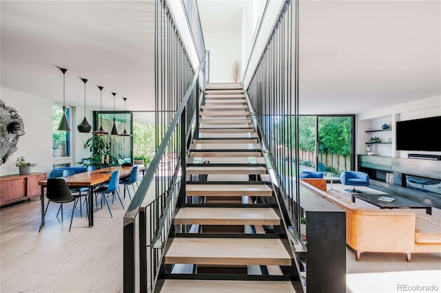 stairway with plenty of natural light, wood finished floors, and expansive windows