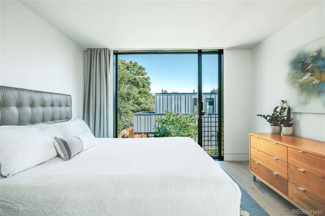 bedroom with wood finished floors, floor to ceiling windows, and access to exterior