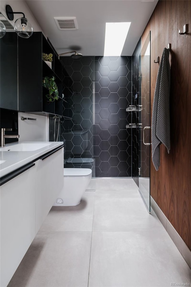 bathroom with tile patterned floors, visible vents, toilet, a tile shower, and vanity