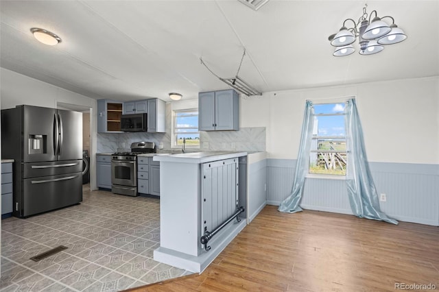 7855 Edison Rd, Yoder, CO 80864 - kitchen featuring appliances with stainless steel finishes, gray cabinetry, plenty of natural light, and a wainscoted wall