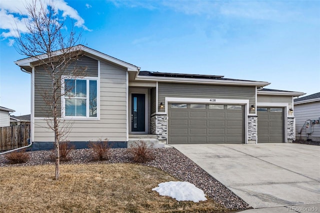 view of front facade with a garage, concrete driveway, fence, and solar panels