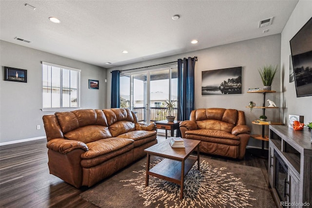 living room with a healthy amount of sunlight, baseboards, visible vents, and wood finished floors