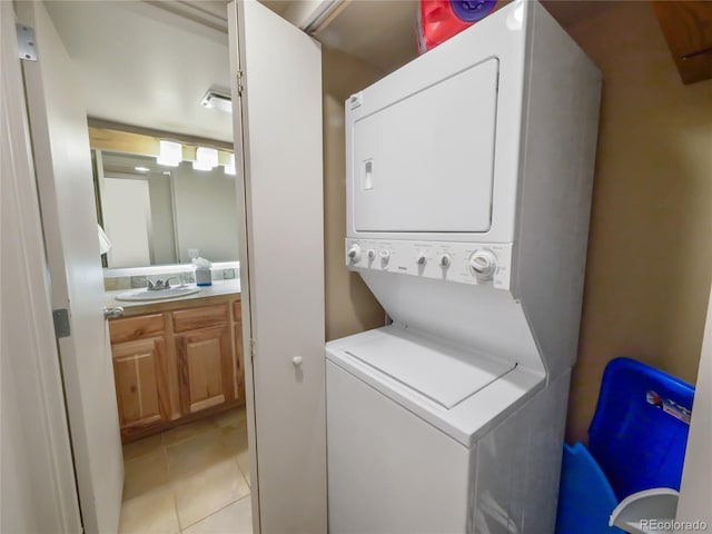 clothes washing area with stacked washer / drying machine, sink, and light tile patterned floors