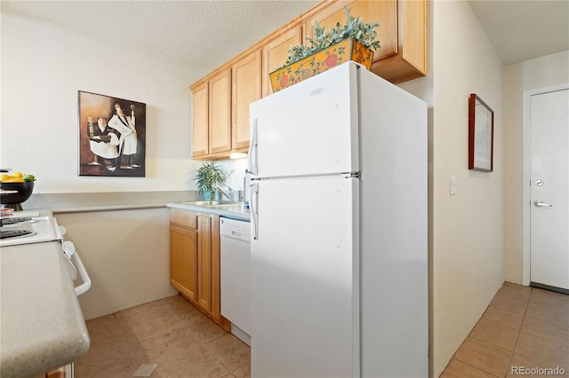 kitchen featuring white appliances, a textured ceiling, light brown cabinetry, and light countertops