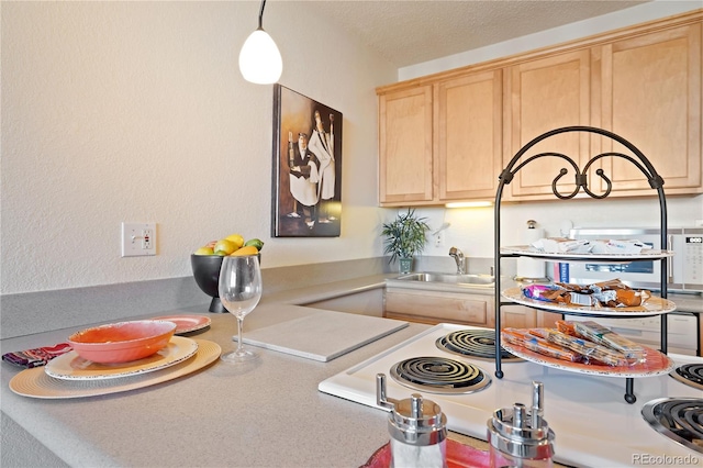 kitchen featuring a sink, hanging light fixtures, light countertops, light brown cabinetry, and a textured ceiling