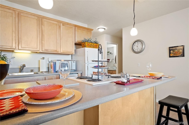 kitchen with white appliances, a sink, light brown cabinetry, light countertops, and a kitchen breakfast bar