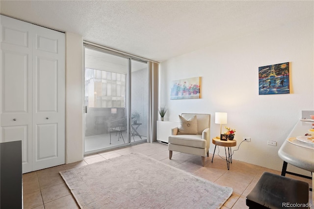 sitting room featuring tile patterned floors, expansive windows, and a textured ceiling