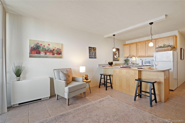 kitchen featuring white appliances, a breakfast bar, a peninsula, light brown cabinetry, and decorative light fixtures