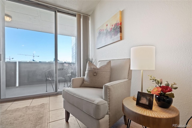 living area featuring tile patterned flooring and a textured wall