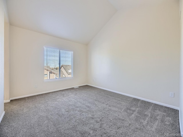 empty room with carpet floors and vaulted ceiling