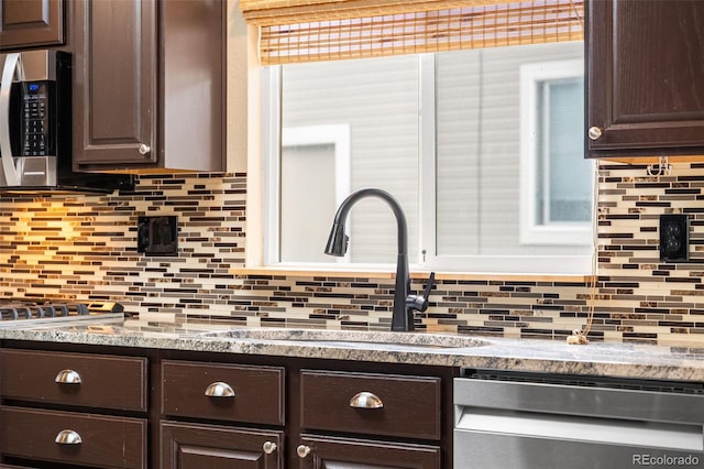 429 Arrowhead Dr, Loveland, CO 80537 - kitchen with appliances with stainless steel finishes, dark brown cabinets, a sink, and backsplash