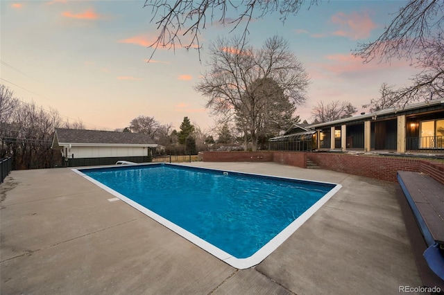 pool at dusk featuring fence, an outdoor structure, a fenced in pool, and a patio