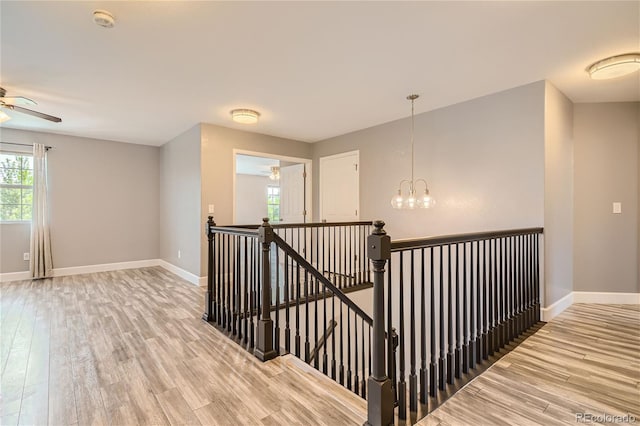 stairs with hardwood / wood-style floors and ceiling fan with notable chandelier