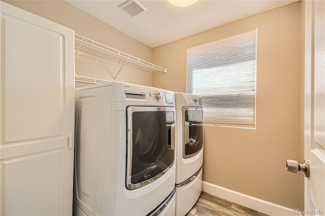 clothes washing area with washer and dryer and light hardwood / wood-style floors