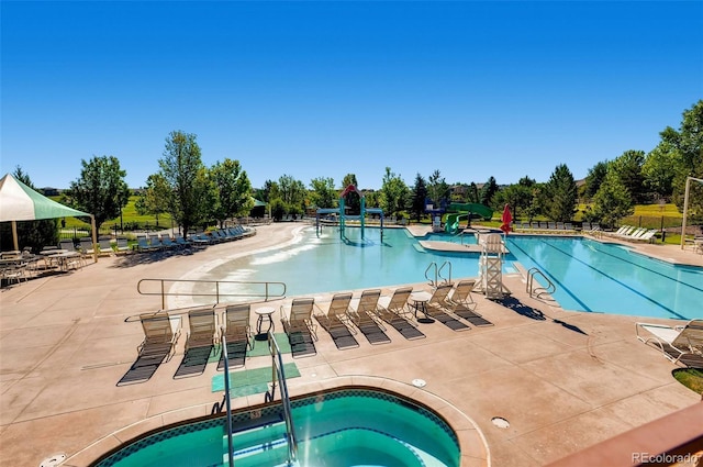 view of swimming pool featuring a patio, a hot tub, and a water slide