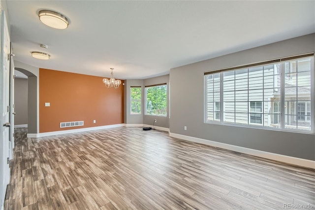 unfurnished room with a notable chandelier and light hardwood / wood-style floors