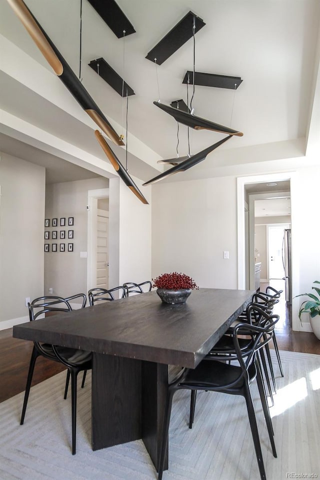 dining room with baseboards, a high ceiling, and wood finished floors