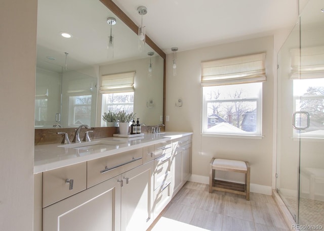 bathroom featuring double vanity, baseboards, a shower stall, and a sink