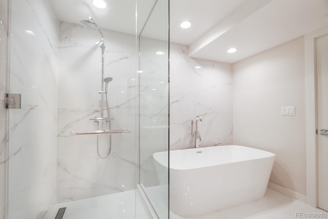bathroom with recessed lighting, a marble finish shower, and a freestanding tub