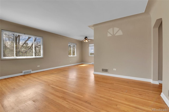 spare room featuring visible vents, arched walkways, light wood-style floors, and ceiling fan