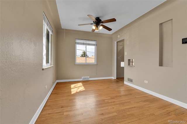 empty room featuring light wood-type flooring, baseboards, ceiling fan, and visible vents