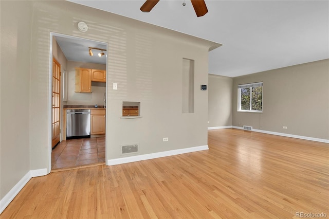 empty room with ceiling fan, visible vents, baseboards, and light wood-type flooring