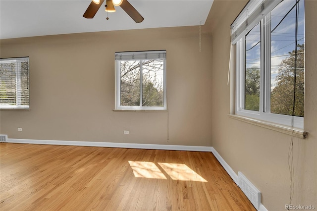 empty room featuring baseboards, visible vents, plenty of natural light, and wood finished floors