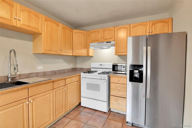 kitchen with under cabinet range hood, stainless steel appliances, tile countertops, and light brown cabinets