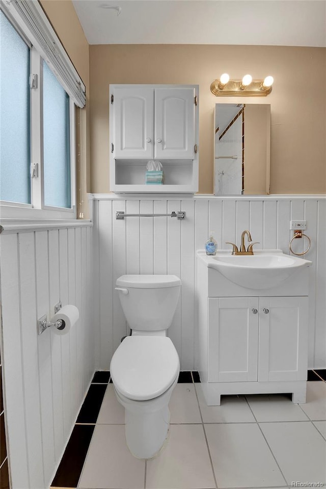 bathroom with vanity, tile patterned flooring, wainscoting, and toilet