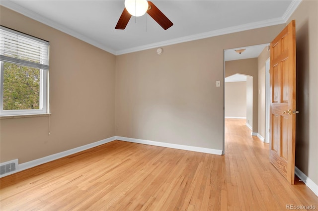 unfurnished room featuring light wood finished floors, a ceiling fan, baseboards, visible vents, and ornamental molding