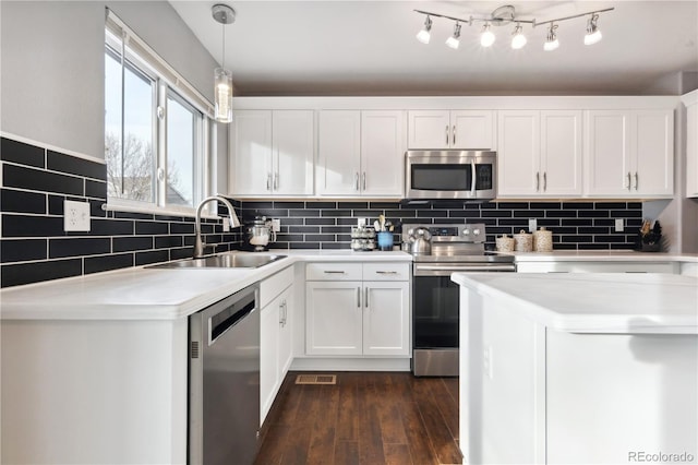 kitchen featuring appliances with stainless steel finishes, pendant lighting, white cabinetry, and sink