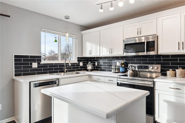 kitchen with pendant lighting, white cabinets, a center island, stainless steel appliances, and sink