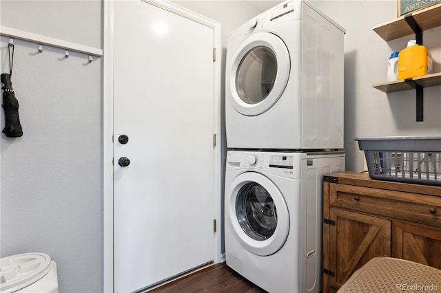 laundry area with stacked washer / drying machine and dark wood-type flooring