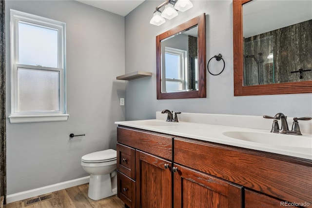 bathroom with toilet, vanity, wood-type flooring, and walk in shower