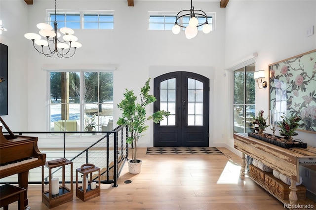 entrance foyer with french doors, light hardwood / wood-style flooring, an inviting chandelier, and a high ceiling